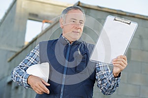 mature supervisor looking at clipboard outdoors