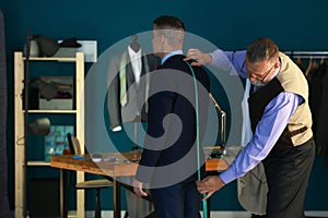 Mature tailor taking client's measurements in atelier photo