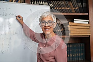 Mature teacher writing on whiteboard