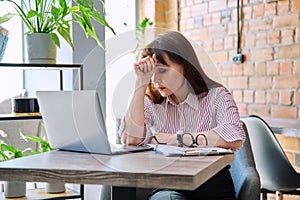 Mature tired worried tense woman at workplace experiencing stress headache