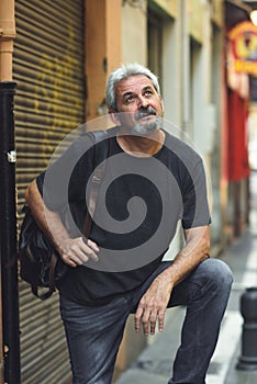 Mature tourist man with travel backpack in urban background.