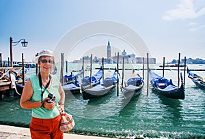 Mature tourist woman stays against row of gondolas