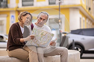 Mature Tourists Couple With Touristic Map Planning Holidays Sitting Outdoor