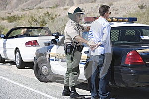 Mature Traffic Cop Arresting Middle Aged Man