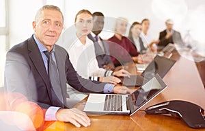 Mature white businessman sitting at meeting and listening to presentation