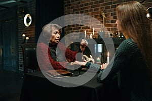 Mature witch using crystal pendulum to predict future for client