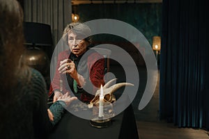 Mature witch using crystal pendulum to predict future for client