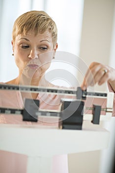 Mature Woman Adjusting Sliding Weight Scale