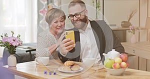 Mature woman and adult successful son having video conversation and smiling . Young man showing his grandmother how