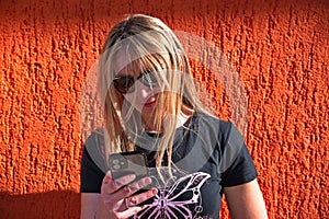 Mature woman against orange background using mobile phone