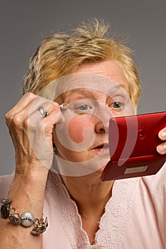 Mature woman applying eye-shadow