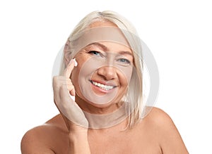 Mature woman applying face cream on background