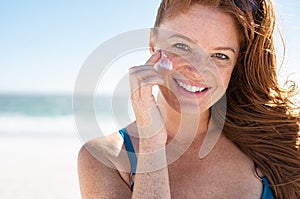 Mature woman applying sunscreen on face photo