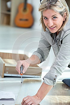 mature woman assembling furniture in new home