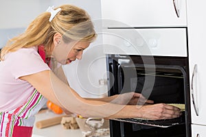 Mature woman baking cookies at home in kitchen