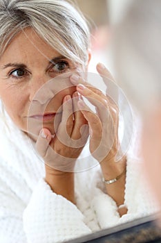 Mature woman in bathrobe taking care of skin