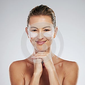 Mature woman, beauty and eye patches on a gray studio background. Skincare, health and female model with face and facial