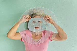 Mature woman with beauty facial mask. Her eyes wide open.