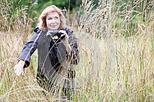 Mature woman with binoculars in high grass, bird watcher, copy space