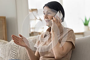 Mature woman blab on cellphone seated on couch