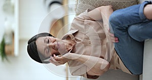 Mature woman blab on phone seated on couch, vertical view