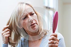 Mature Woman With Brush Concerned About Hair Loss