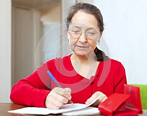 Mature woman is calculated family budget photo