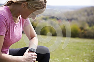 Mature Woman Checking Activity Tracker Whilst On Run