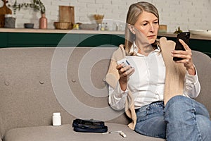 Mature woman checking glucometer results on internet and looking involved