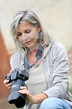 Mature woman checking pictures on screen camera