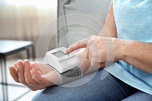 Mature woman checking pulse with medical device at home