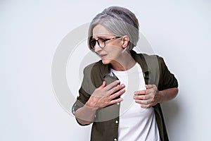 Mature woman with chest, heart problems. Senior grey haired woman with short hair suffering from aneurism. Online