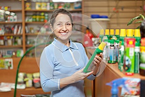 Mature woman chooses fertilizers at store