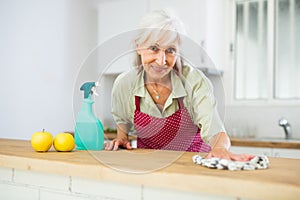 Mature woman cleaning kitchen table at home