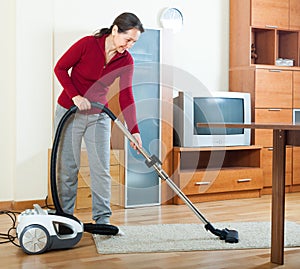 Mature woman cleaning with vacuum cleaner