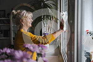 Mature woman cleaning windows in her home