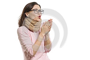 Mature woman cold, wearing a scarf warming her hands with hot breath, white background isolated.