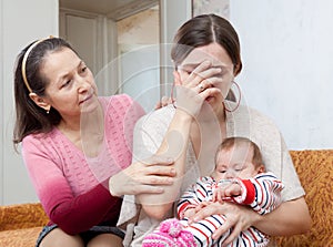 Mature woman comforts crying daughter with baby photo