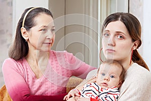 Mature woman comforts sad adult daughter photo