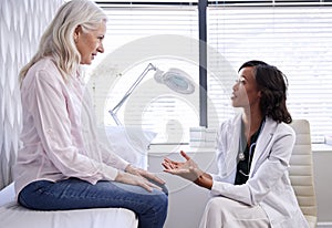 Mature Woman In Consultation With Female Doctor Sitting On Examination Couch In Office photo