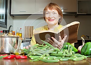 Mature woman cooking okra with cookbook i