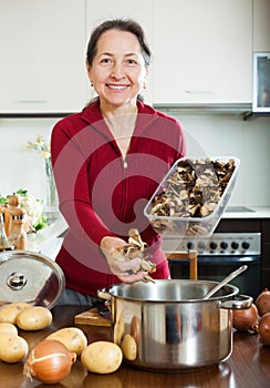 Mature woman cooking soup with dried mushrooms