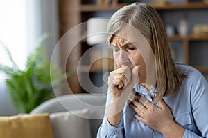 Mature woman coughing, feeling unwell in living room