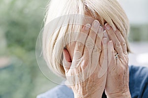 Mature woman covering her face with her hands.