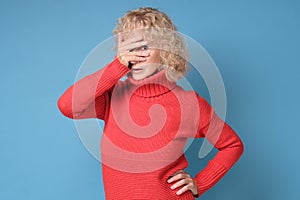 Mature woman covering her face with his hands and spies, hiding her eyes