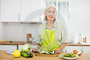 Mature woman cutting fresh vegetables for dinner