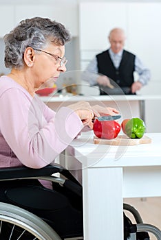mature woman cutting tomato in kitchen