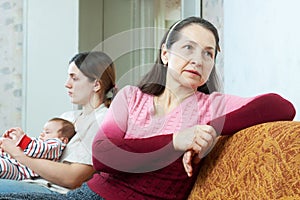 Mature woman and daughter with baby having conflict