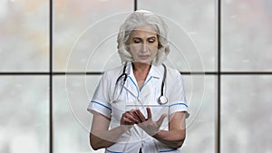 Mature woman doctor using glass tablet pc.