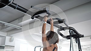 Mature woman is doing pull-ups with a narrow grip in gym. Sport concept.